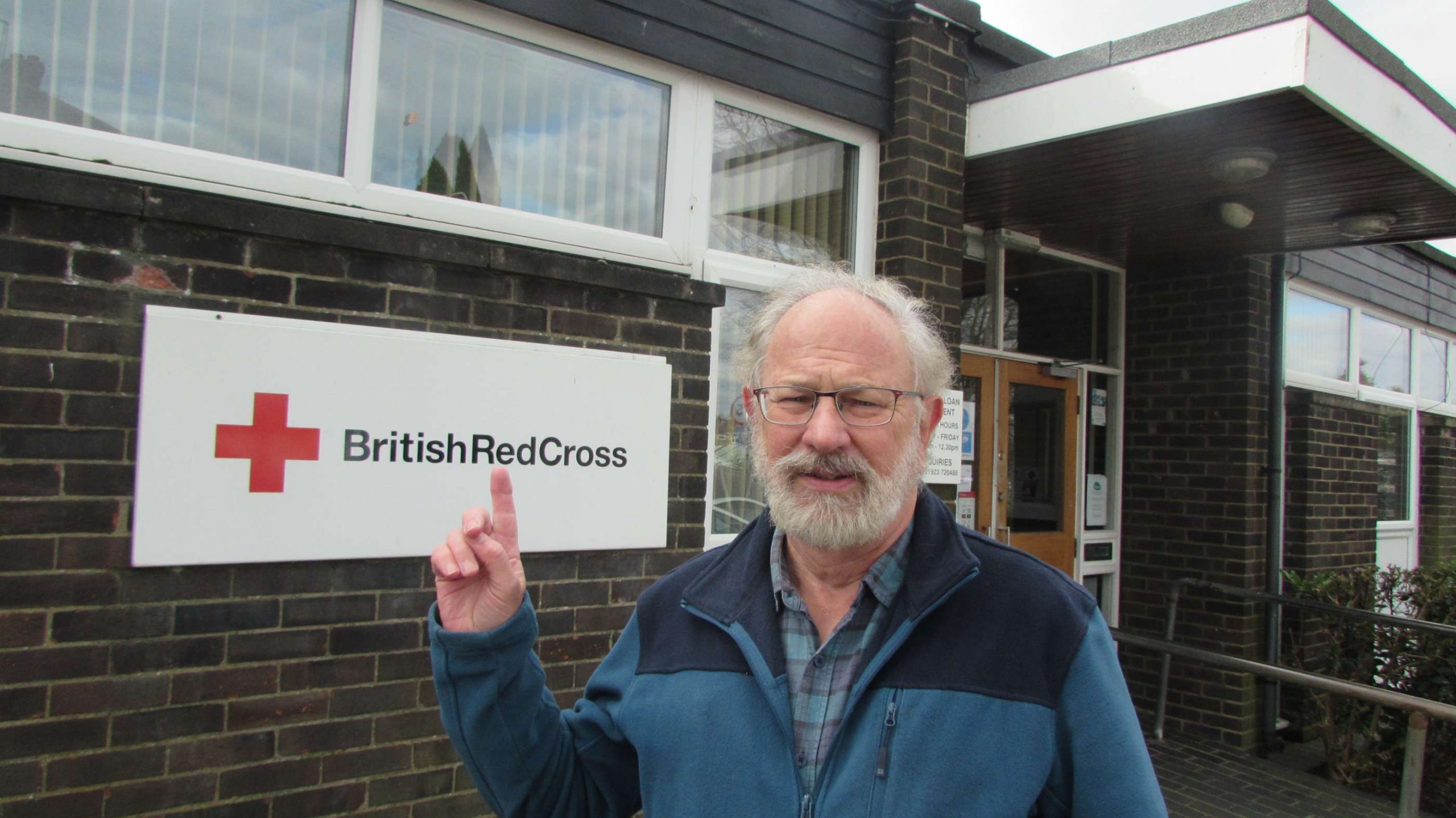 Chris points to the British Red Cross sign at the hall in Croxley Green